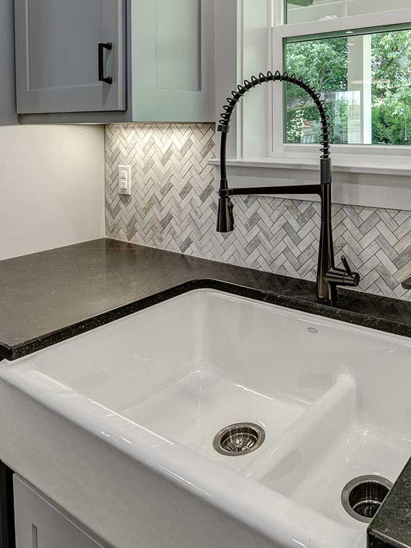 Farmhouse sink and herringbone tile detail in a Wanoca Builders home